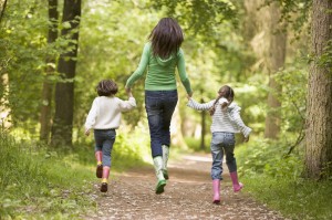 Mother and daughters skipping on path smiling