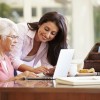 young woman helping older woman with computer