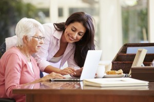 young woman helping older woman with computer