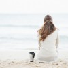 woman sitting on beach facing the sea