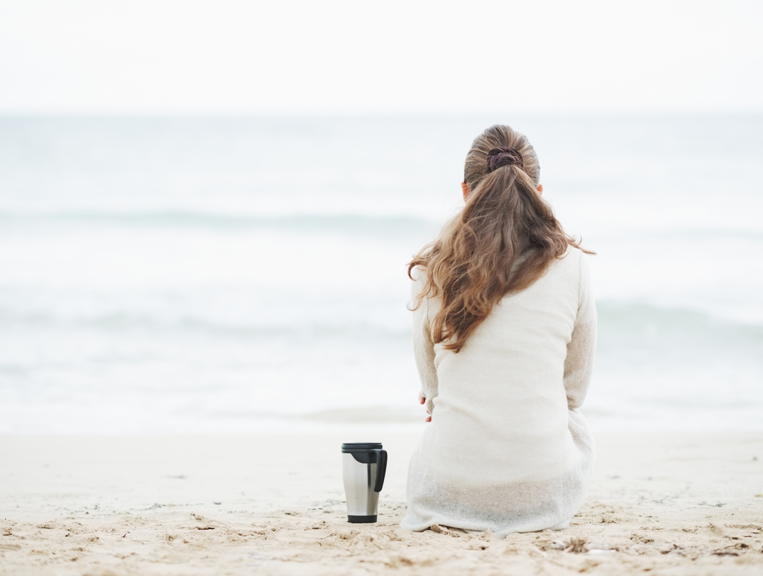 woman sitting on beach facing the sea
